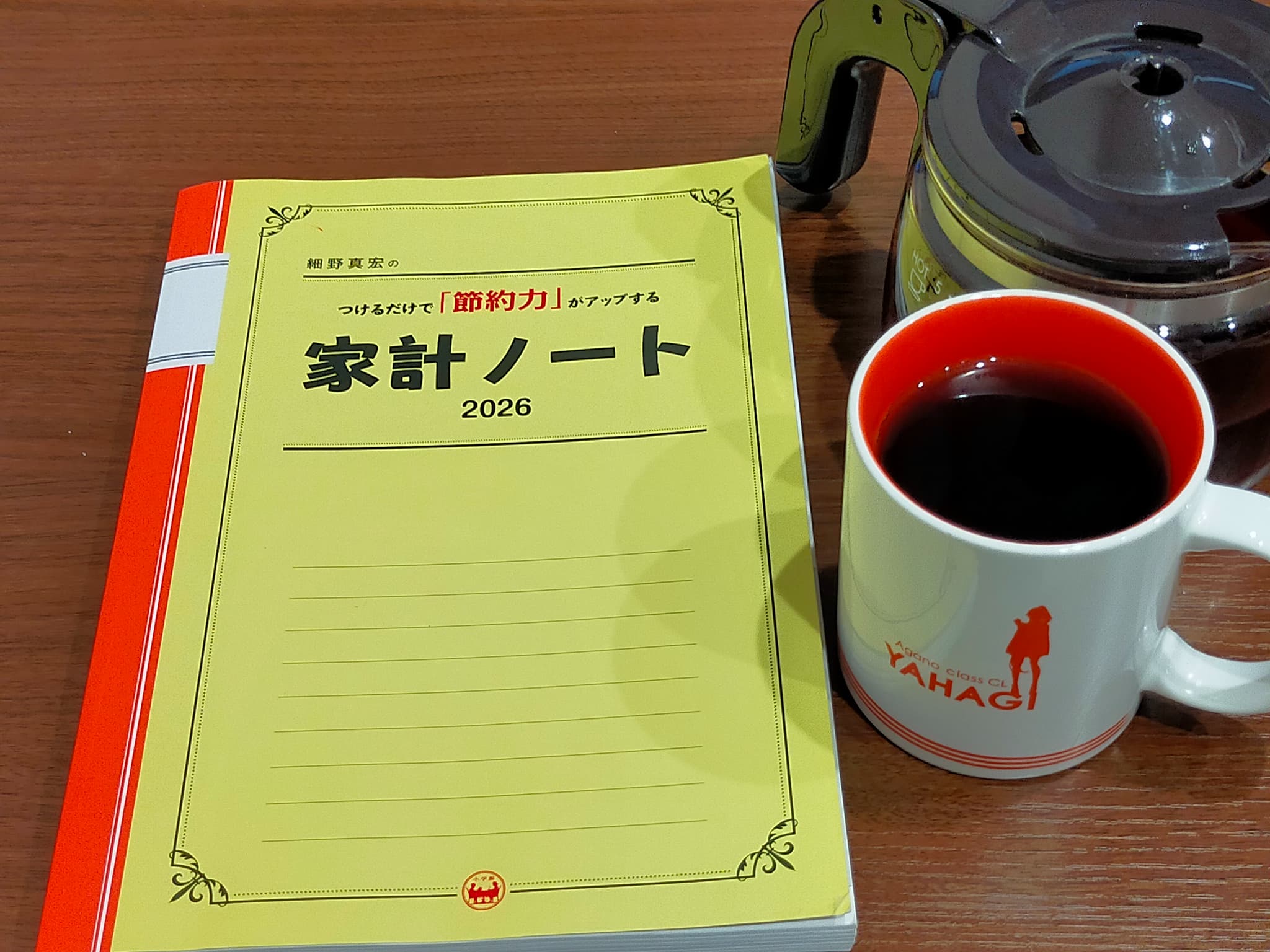 コーヒーを飲みつつ家計ノートで2026年9月末の資産状況を整理している様子